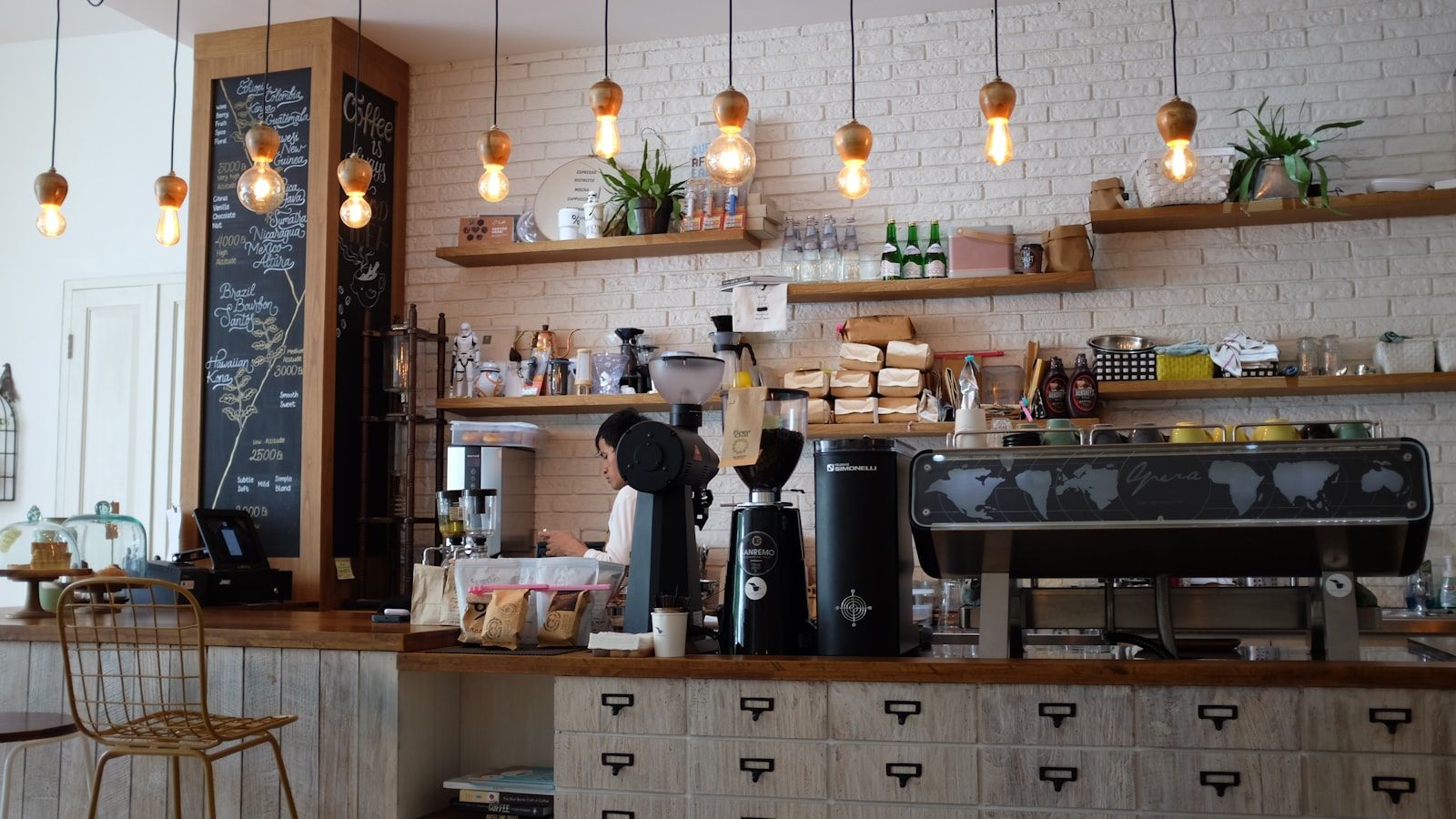 Bar z rzędem wiszących żarówek, ekspresem i tablicą z menu
