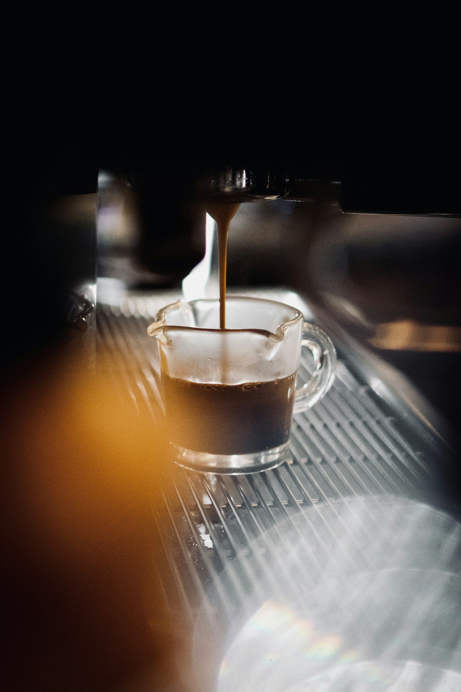 Dwie strugi espresso spływające z kolby do szklanego naczynia