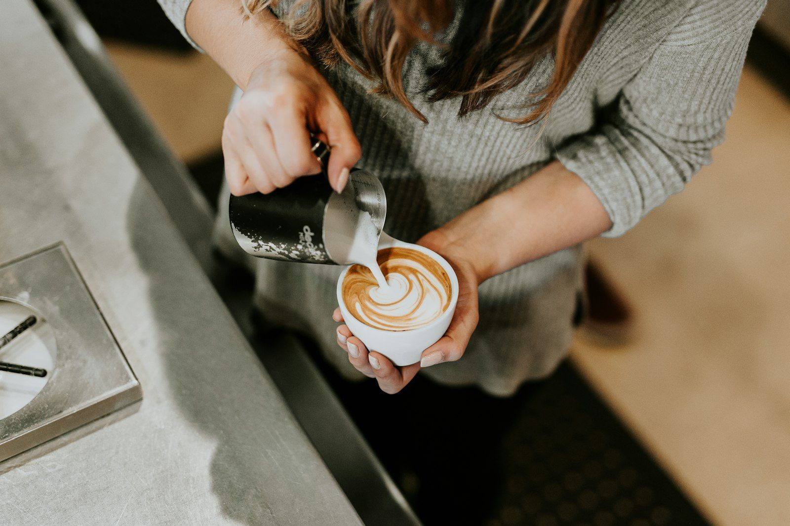 Mleko wylewane w spiralę na powierzchnię espresso w filiżance